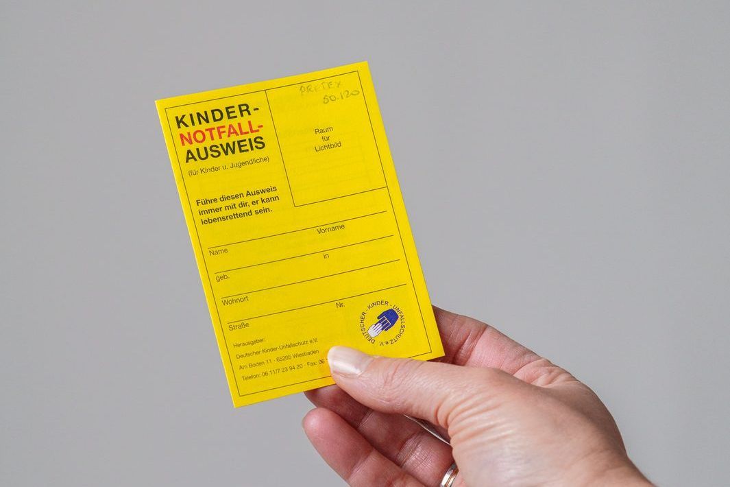 Ein gelber Kinder-Notfallausweis wird in der Hand gehalten
