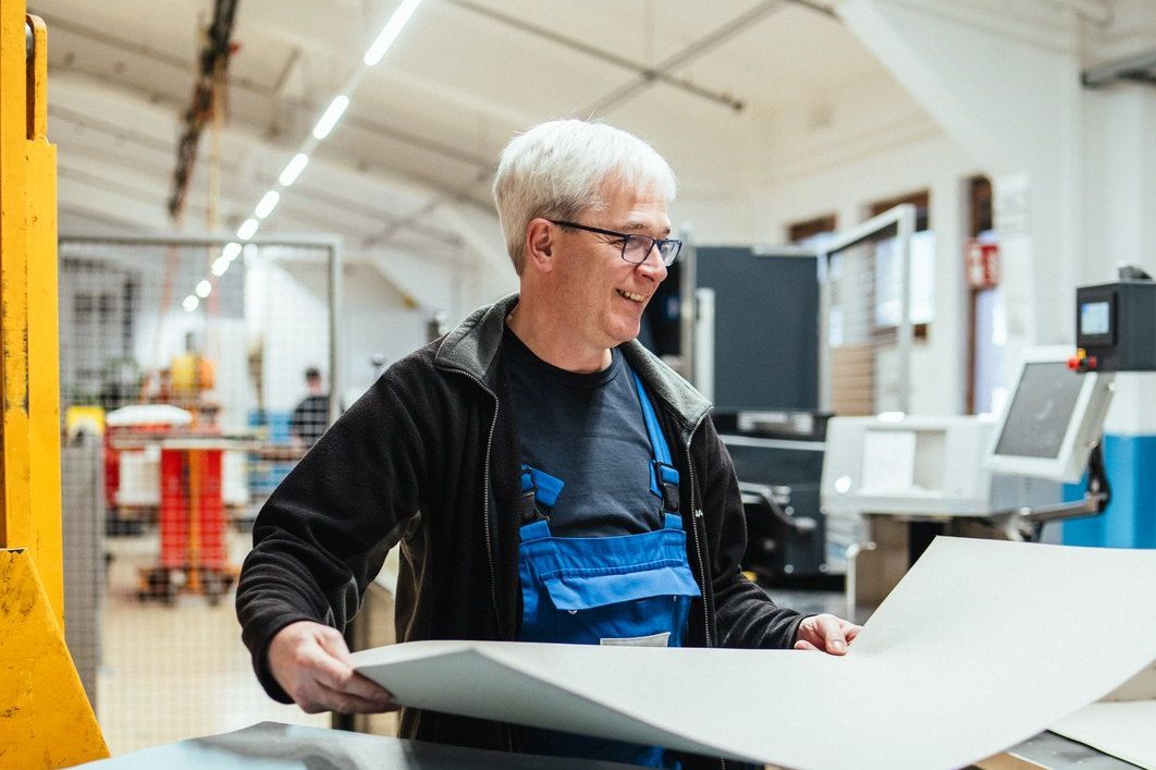 Mitarbeiter hebt einen großen Papierbogen von einem Stapel in der Lahnpaper-Produktion